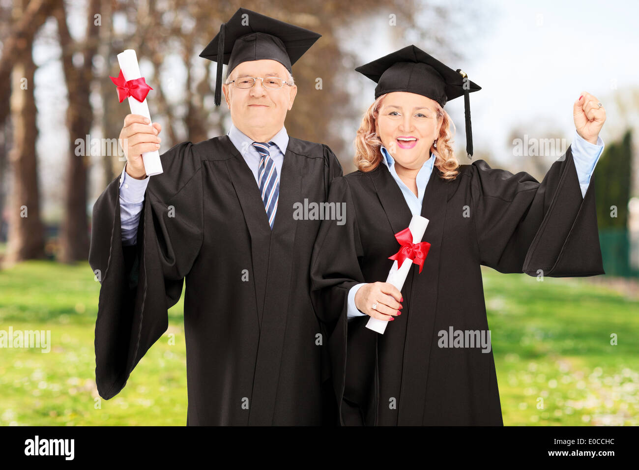 Coppia matura per celebrare i loro diplomi e loro graduazioni in posizione di parcheggio Foto Stock