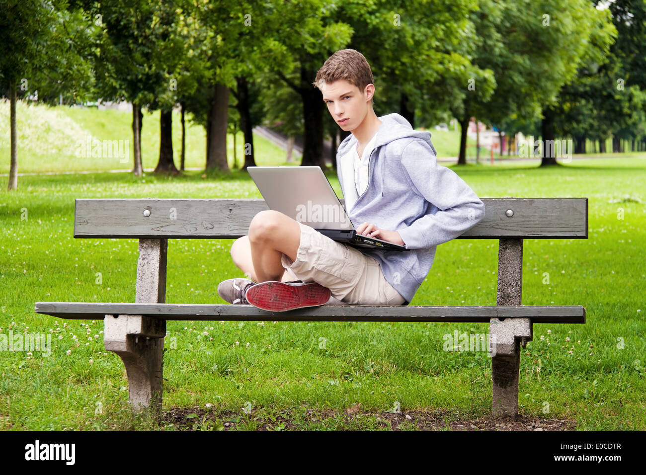 Un adolescente con il computer portatile al di fuori Foto Stock