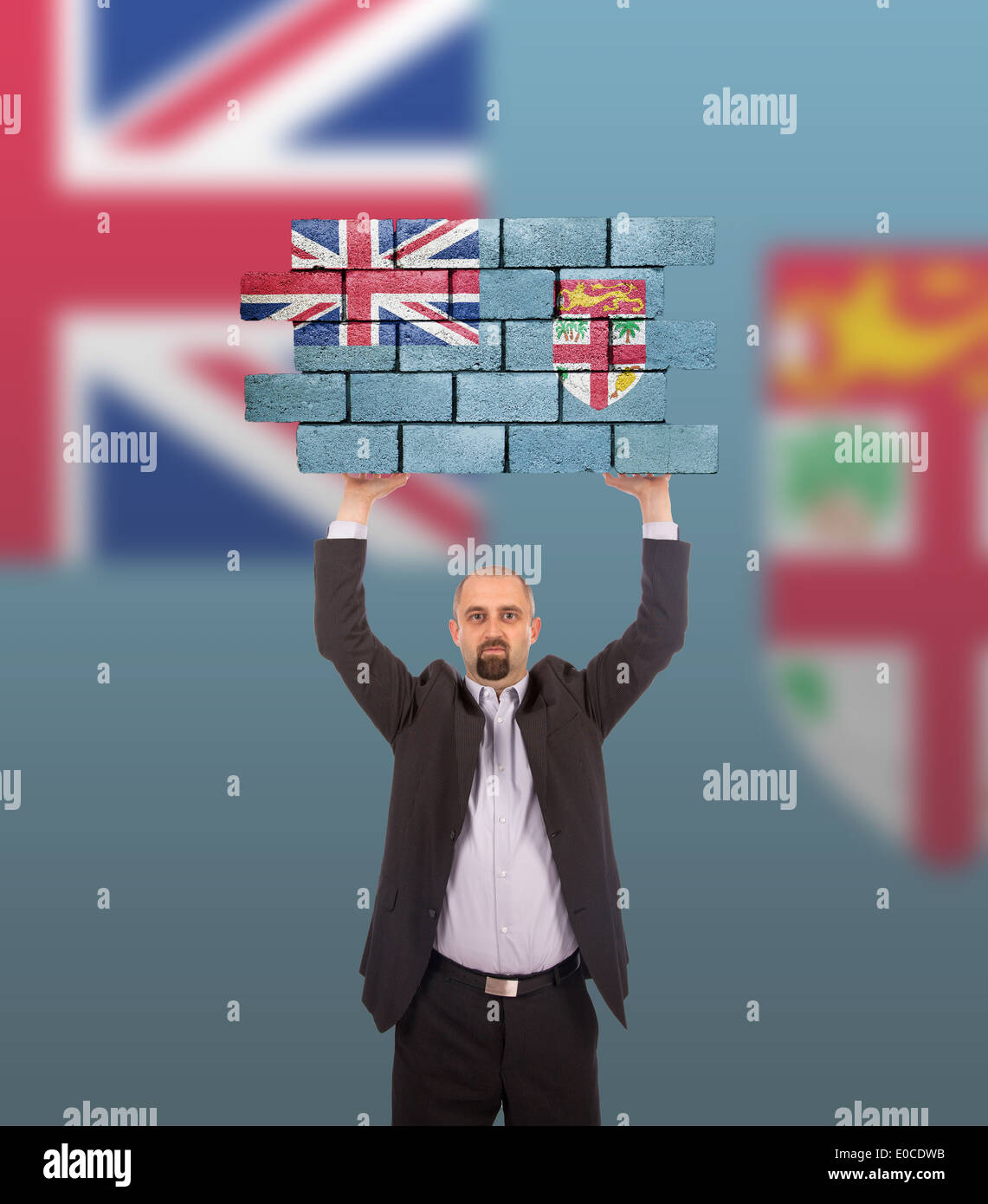 Imprenditore tenendo un grande pezzo di un muro di mattoni bandiera delle isole Figi isolata sulla bandiera nazionale Foto Stock