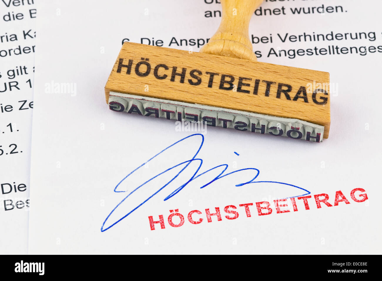 Un francobollo di legno si trova su un documento. Etichetta Hoechstbeitrag, Ein Stempel aus Holz liegt auf einem Dokument. Aufschrift Hoechstbeitr Foto Stock