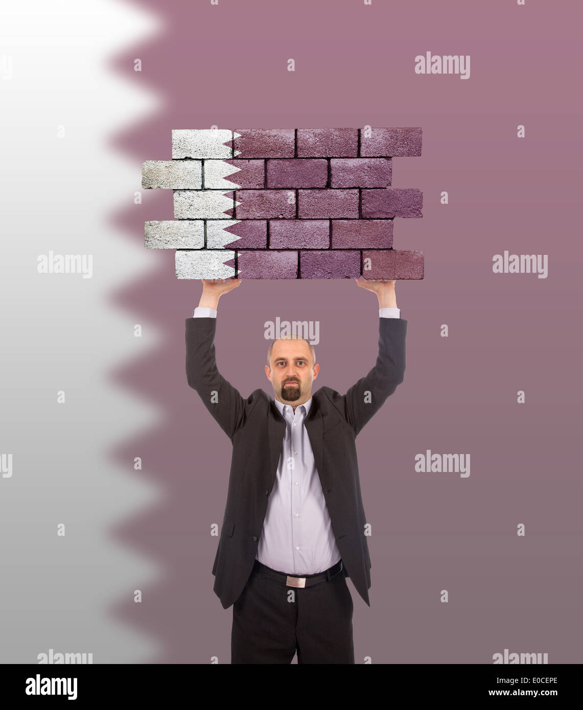 Imprenditore tenendo un grande pezzo di un muro di mattoni bandiera del Qatar isolata sulla bandiera nazionale Foto Stock