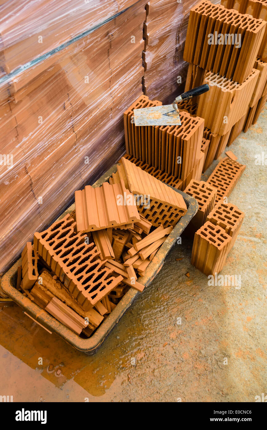 Lavoratore edile con la parete di un guscio in costruzione massiccia. Muro di mattoni di una casa unifamiliare Foto Stock