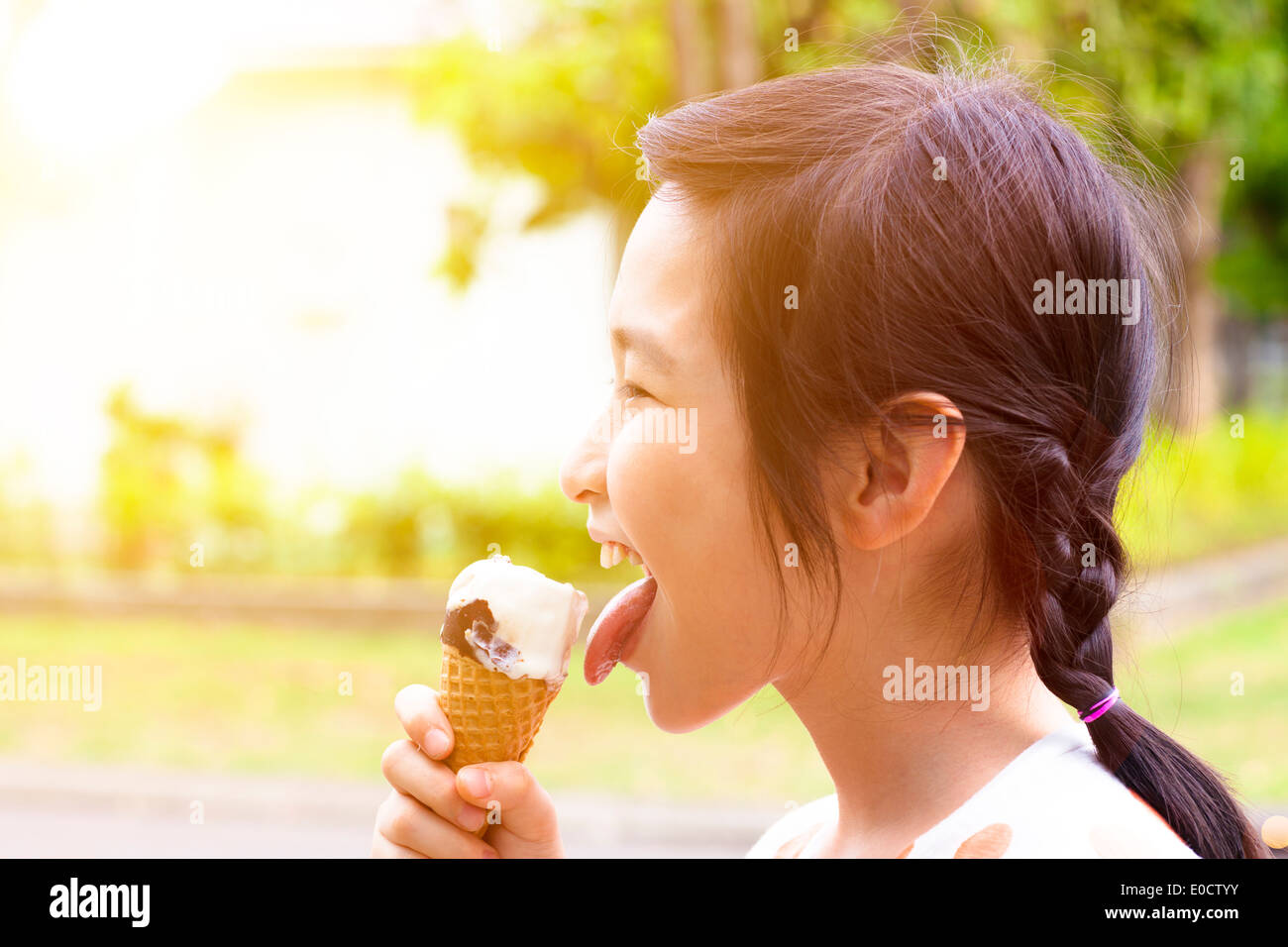 Felice bambina mangiare ghiaccioli con sfondo al tramonto Foto Stock