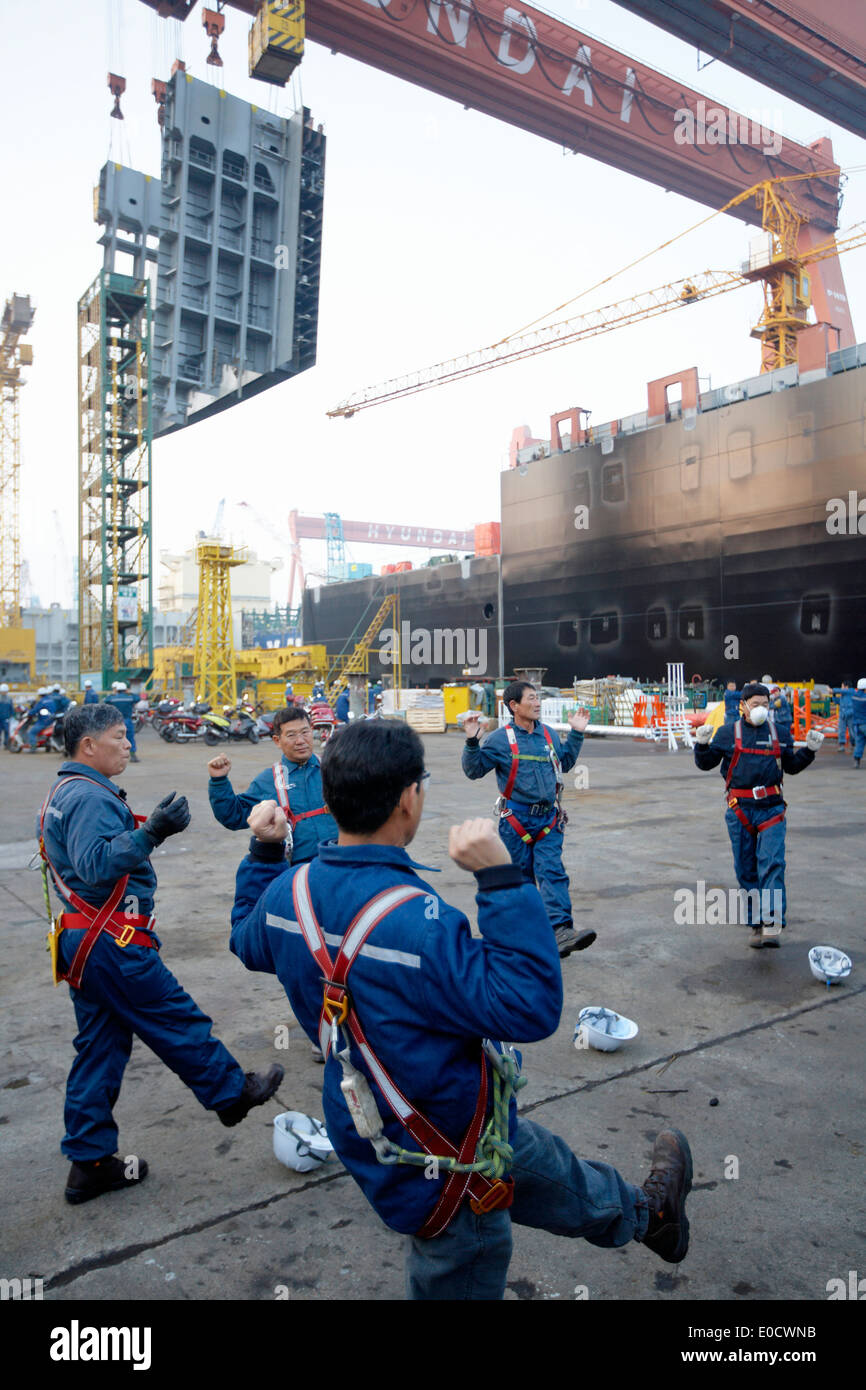 I lavoratori del cantiere facendo esercizi del mattino prima di shift, modulare di produzione presso il più grande cantiere navale del mondo Hyundai Heavy Ind Foto Stock