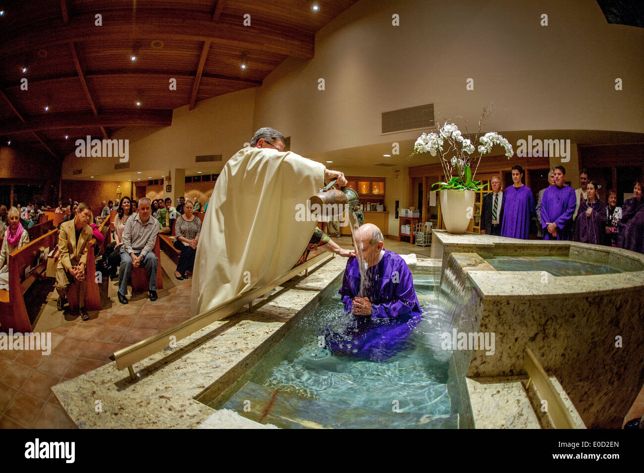Come la sua congregazione di orologi, il parroco di San Timoteo della Chiesa Cattolica, Laguna Niguel, CA, battezza un catecumeno, o una persona che desidera diventare un cattolico. Nota fonte battesimale. Foto Stock
