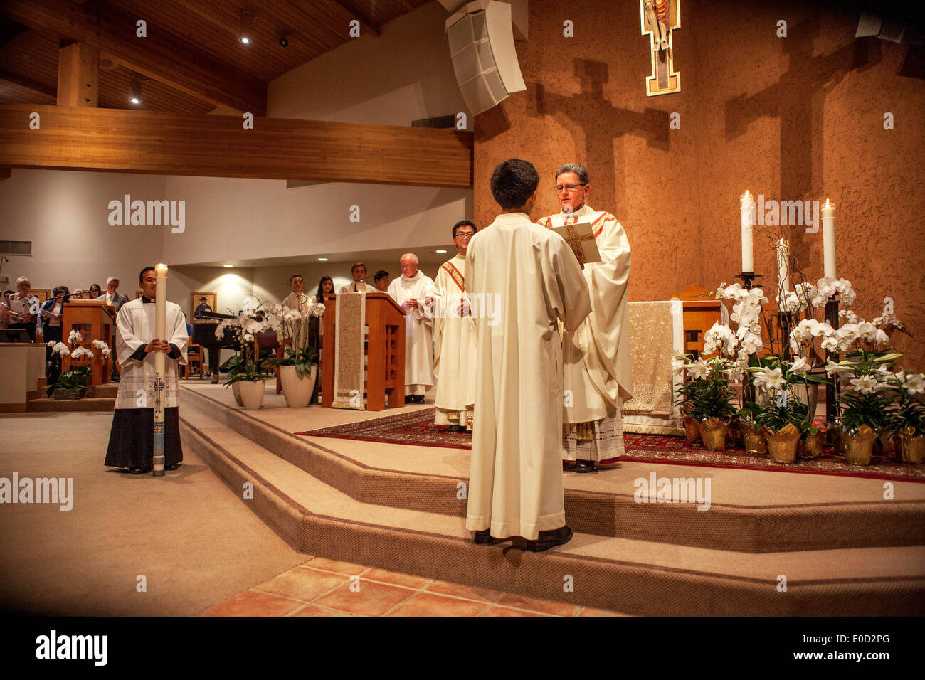 Il parroco di San Timoteo della Chiesa Cattolica, Laguna Niguel, CA, legge dal Vangelo alla sua congregazione durante la conduzione di massa. Nota seminarista intern a sinistra tenendo premuto il cerimoniale e coro in background. Foto Stock