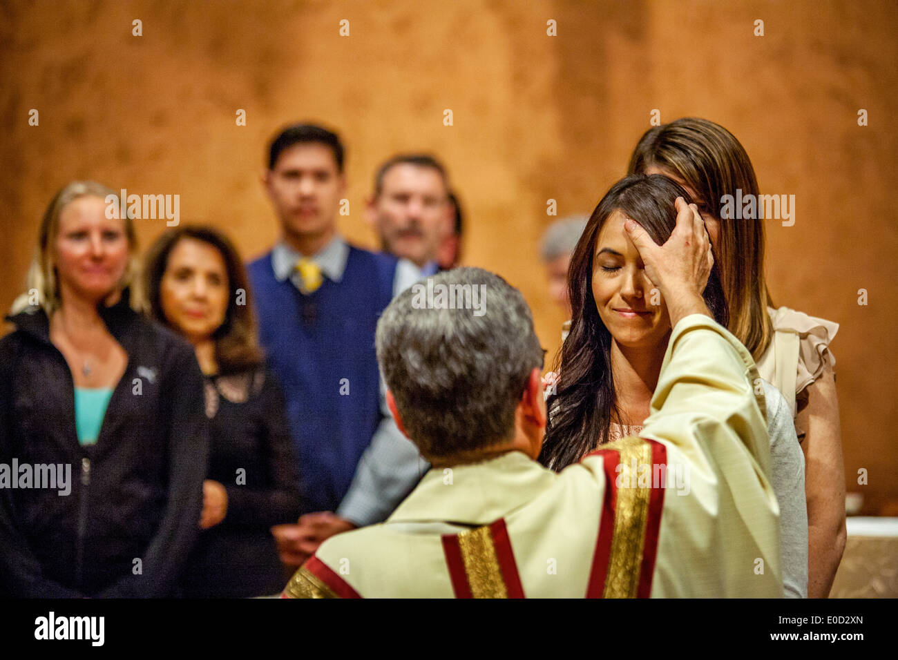 Il parroco di San Timoteo della Chiesa Cattolica, Laguna Niguel, CA, benedice un nuovo membro della congregazione la notte del suo battesimo. Nota altri nuovi membri a sinistra. Foto Stock