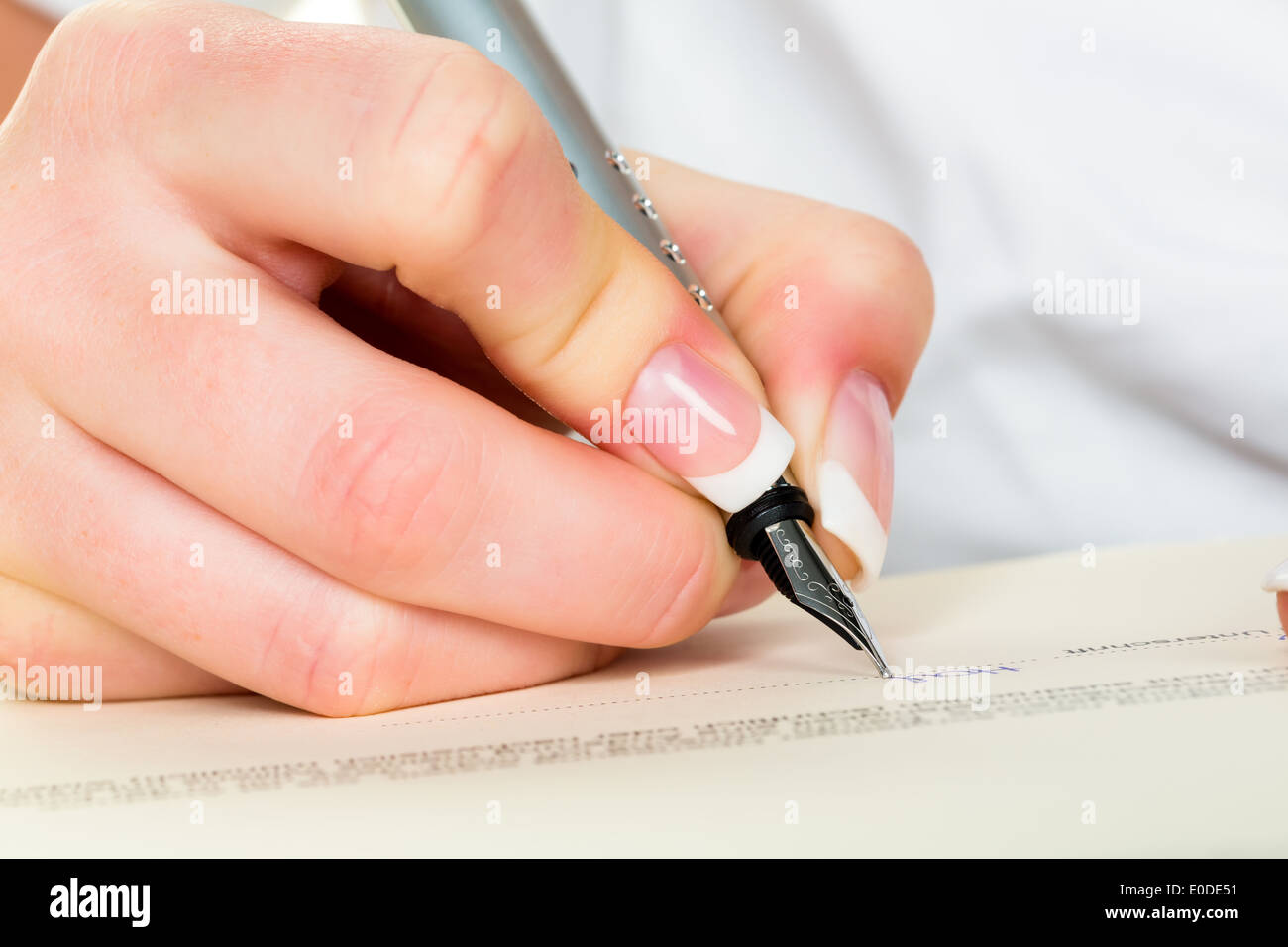 Una donna firma un contratto o un testamento con una fontana-pen., Eine Frau unterschreibt einen Vertrag oder ein testamento mit einer Foto Stock