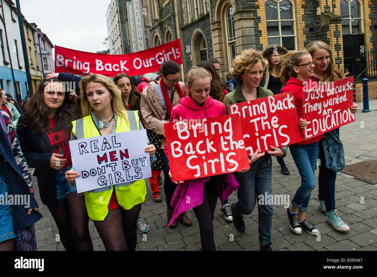 Aberystwyth, Wales UK, sabato 10 maggio 2014 centinaia di ragazze e donne di tutte le età e tutti indossano rosso, hanno marciato per le strade di Aberystwyth Sabato 10 Maggio 2014 a sostegno dell'assenza di ragazze adolescenti rapiti da Boko Haram estremisti islamici in Nigeria. Azienda fatti a mano i segni hanno elaborato dalla città orologio attraverso il castello e si è conclusa sul lungomare. Credito: keith morris/Alamy Live News Foto Stock