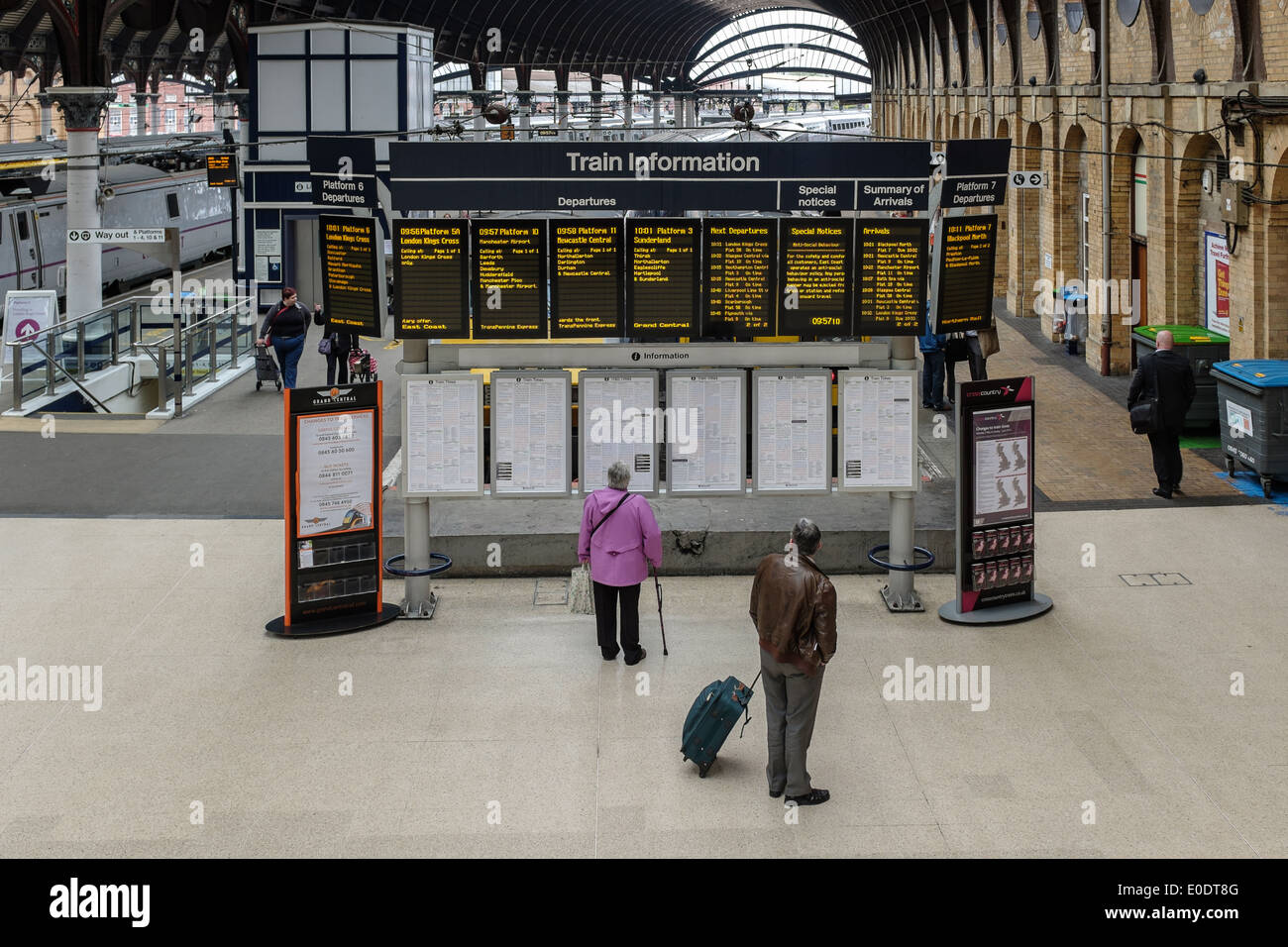 Due adulti più anziani controllare gli orari dei treni sul dot matrix consente di visualizzare e stampare gli orari presso la stazione di York, Inghilterra GRAN BRETAGNA Yorkshire Regno Unito. Foto Stock