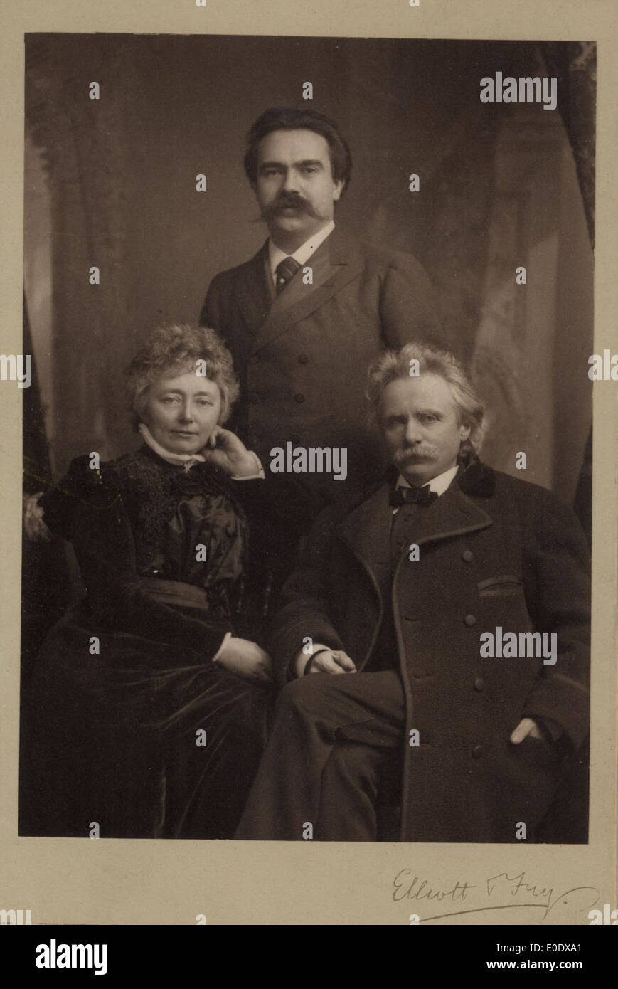 Questa fotografia mostra Nina e Edvard Grieg insieme al violinista russo Adolph Brodskij. Il trio è catturato in un ambiente musicale, probabilmente eseguendo o interagendo durante un evento significativo tra la fine del XIX e l'inizio del XX secolo. L'immagine riflette il loro significato culturale e musicale durante il periodo. Foto Stock
