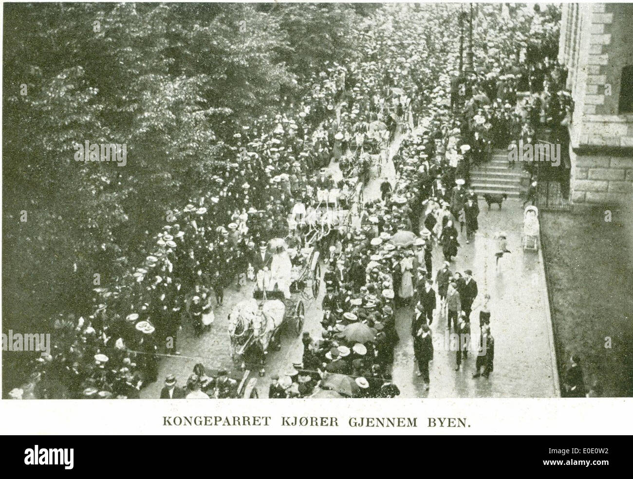 Una fotografia che cattura il re e la regina guidando attraverso la città, forse durante una visita reale. L'immagine mostra la coppia reale in una carrozza aperta, passando per una strada della città, probabilmente presa all'inizio del XX secolo. Foto Stock