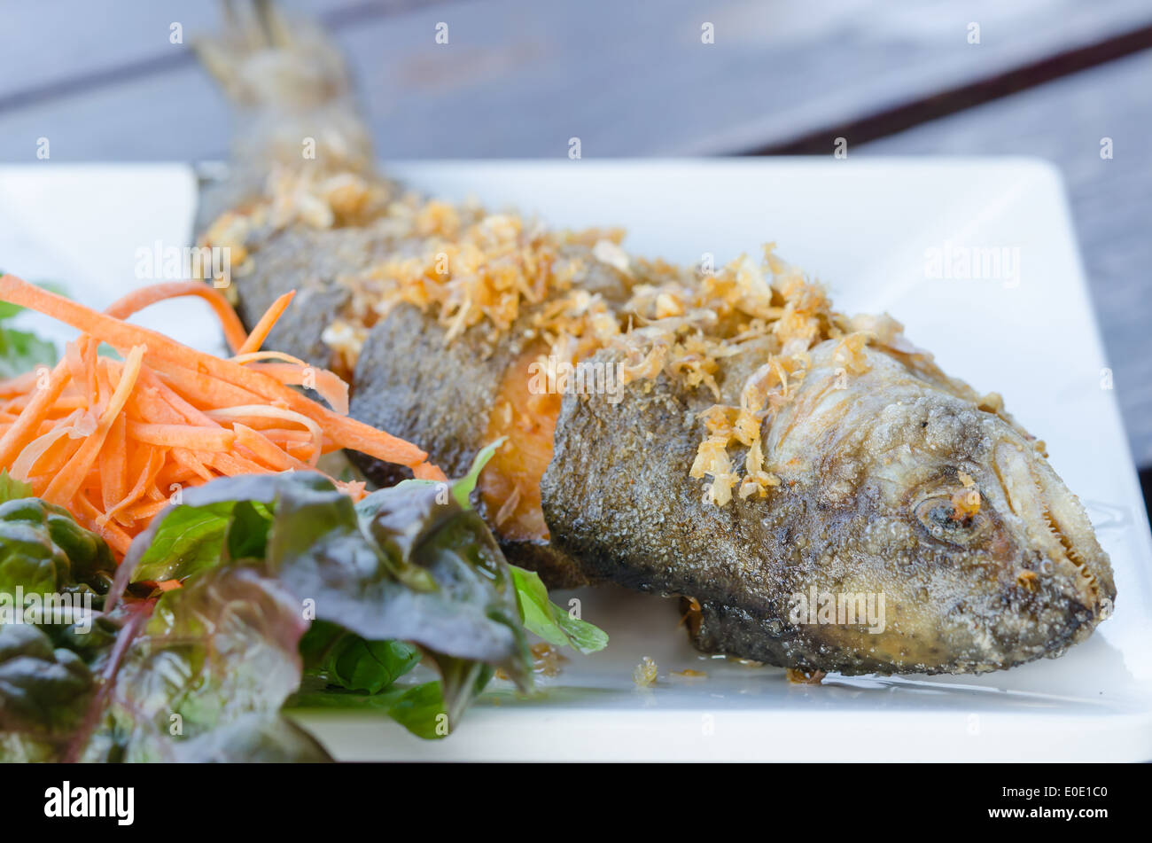 Pesce fritto e aglio servita con verdure fresche sul piatto bianco Foto Stock