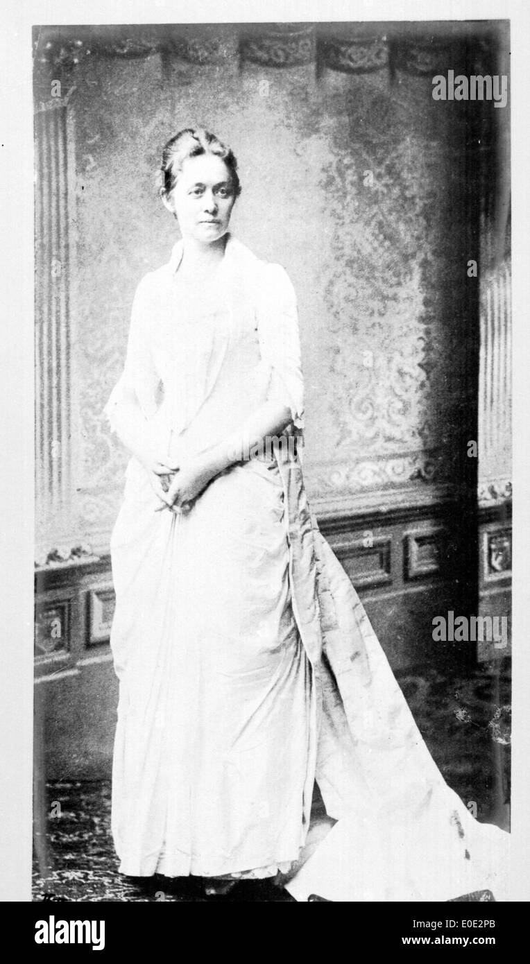 Una fotografia vintage in bianco e nero di una donna in piedi in un abito bianco, che cattura un momento di eleganza e stile dei primi anni del XX secolo. Foto Stock Una fotografia vintage in bianco e nero di una donna in piedi in un abito bianco, che cattura un momento di eleganza e stile dei primi anni del XX secolo. Foto Stock