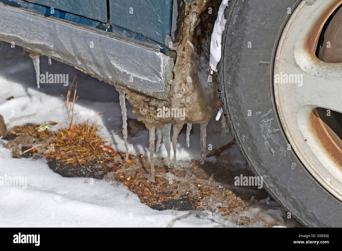 Una vettura con ghiaccioli appesi da essa inizia un disgelo invernale Foto Stock