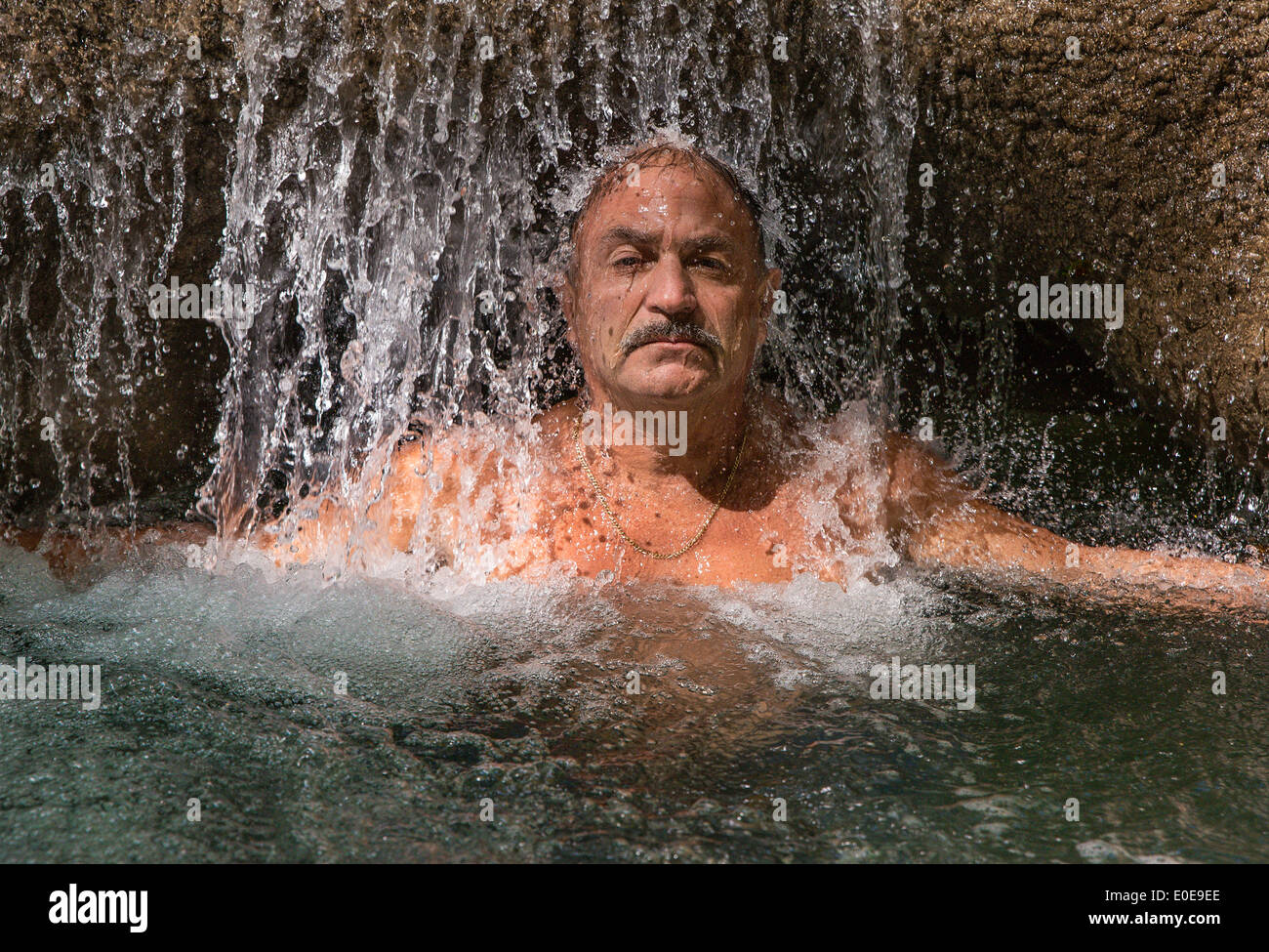 L'uomo gode di un rinfrescante massaggio in acqua a Mayfield Falls, Glenbrook, Giamaica Foto Stock