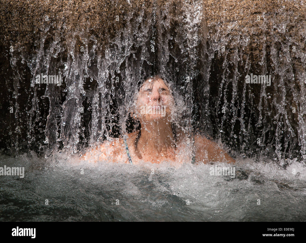 La donna gode di una rinfrescante massaggio in acqua a Mayfield Falls, Glenbrook, Giamaica Foto Stock
