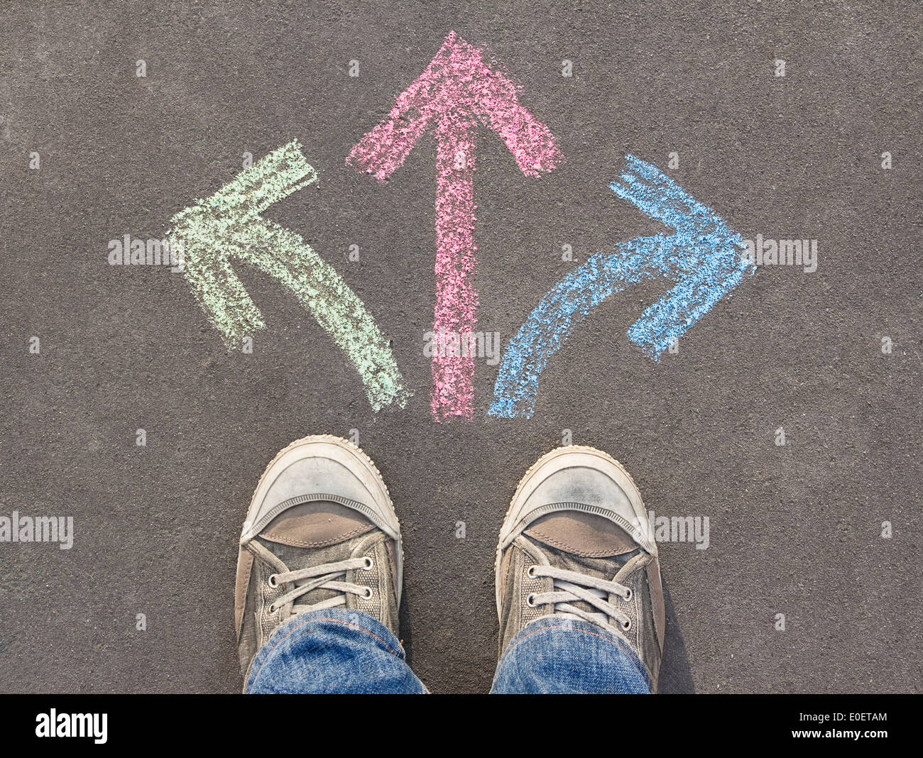 Prendere decisioni, scarpe permanente sulla strada di gesso dipinto frecce Foto Stock