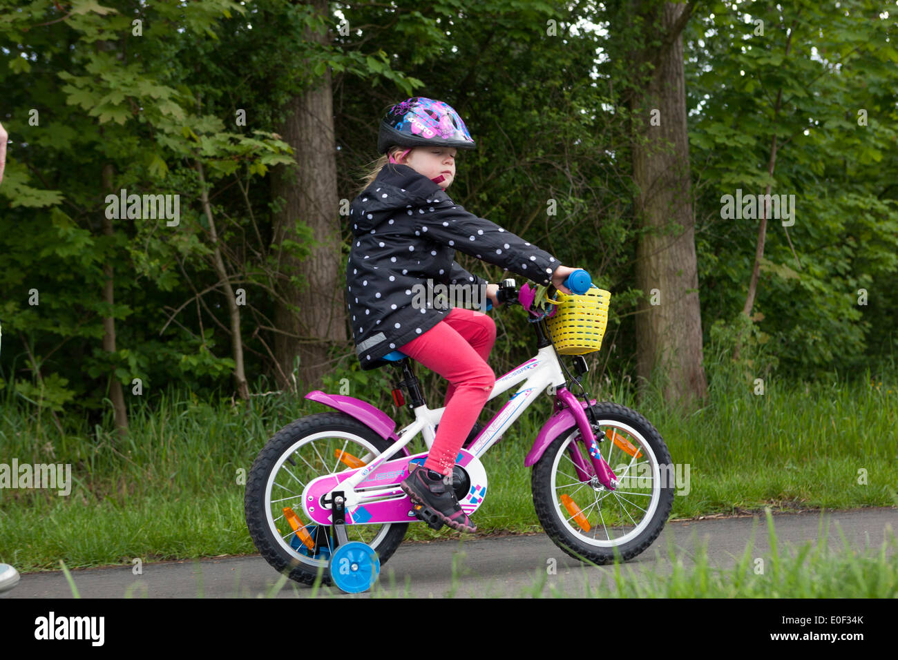 Bambino in bicicletta, pista ciclabile, ragazza in bicicletta, bicicletta per bambini con casco Foto Stock
