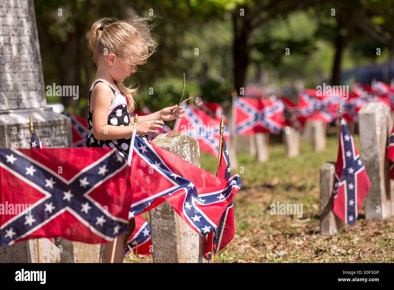 Una giovane ragazza si erge tra bandiere Confederate decorare tombe dei soldati uccisi durante la Guerra Civile americana durante Confederate Memorial Day eventi al cimitero di Magnolia Aprile 10, 2014 in Charleston, Sc. Confederate Memorial Day onora la circa 258,000 soldati confederati che morì durante la Guerra Civile Americana. Foto Stock