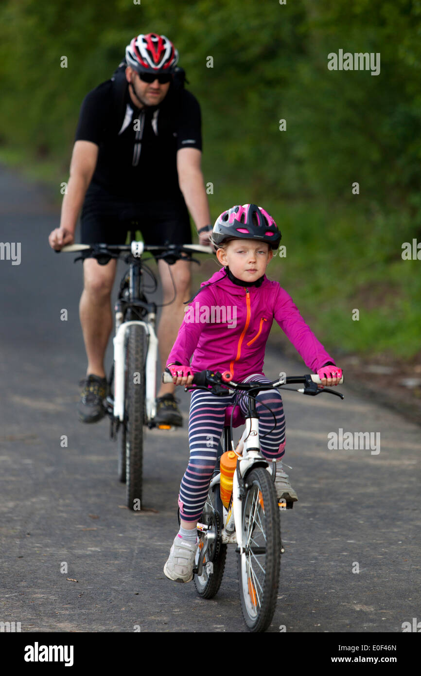 Persone. Padre e bambino su una pista ciclabile, stile di vita sportivo ricreativo. Bicicletta per bambini con casco Foto Stock