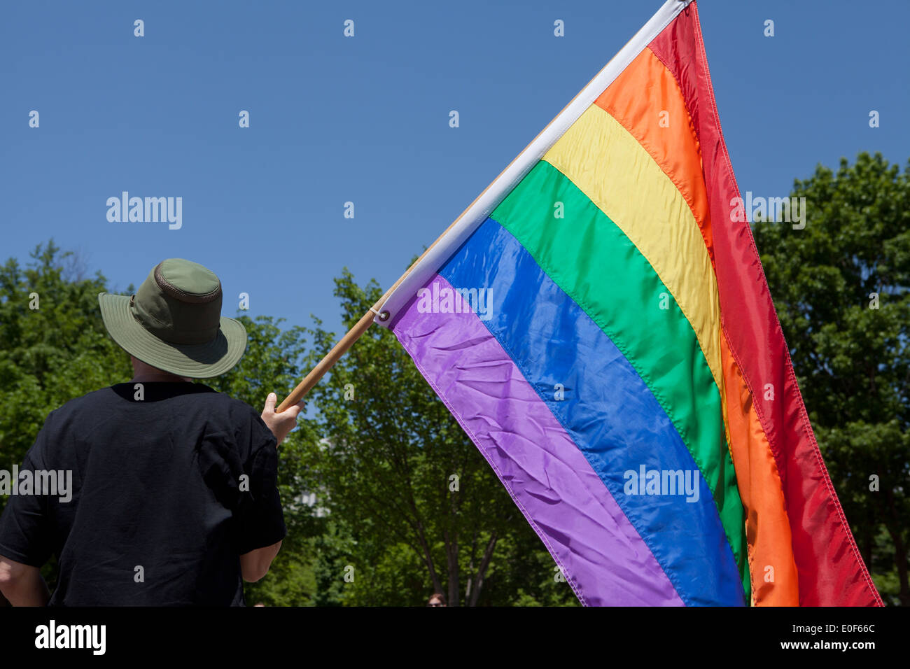 Persona in possesso di una bandiera arcobaleno a LGBT rally - Washington DC, Stati Uniti d'America Foto Stock