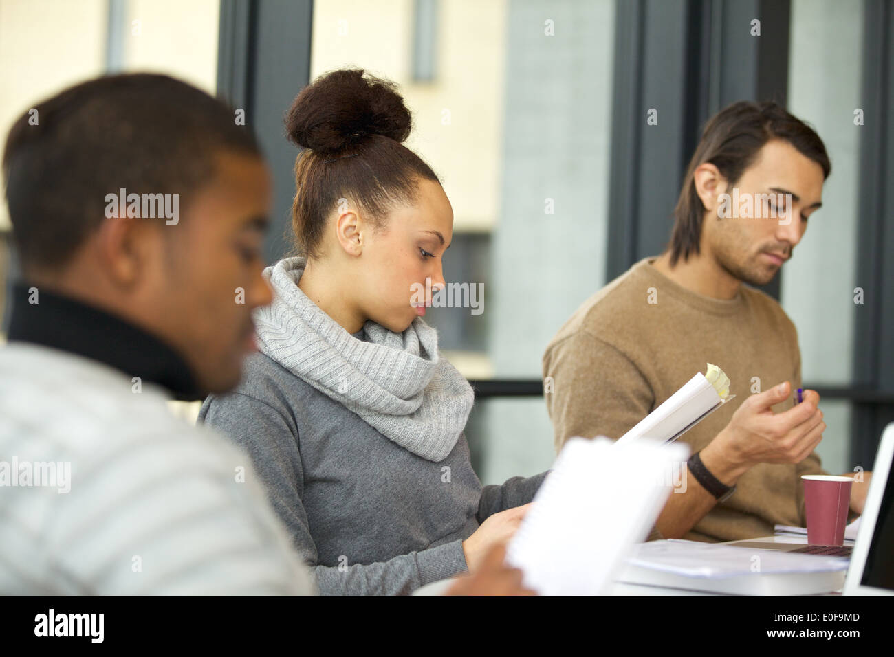 Giovane africano donna americana leggere le note con i compagni di classe lo studio intorno nella biblioteca universitaria. Studenti in preparazione per l'esame. Foto Stock