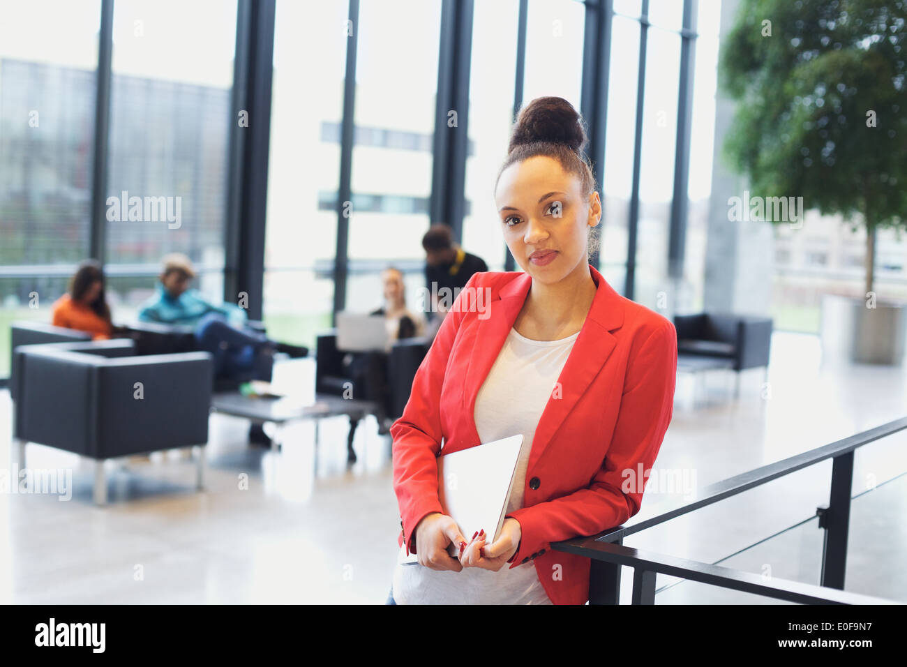 Certi giovani afro american donna che mantiene un notebook in piedi da una ringhiera guardando la fotocamera. Giovane imprenditrice in ufficio. Foto Stock