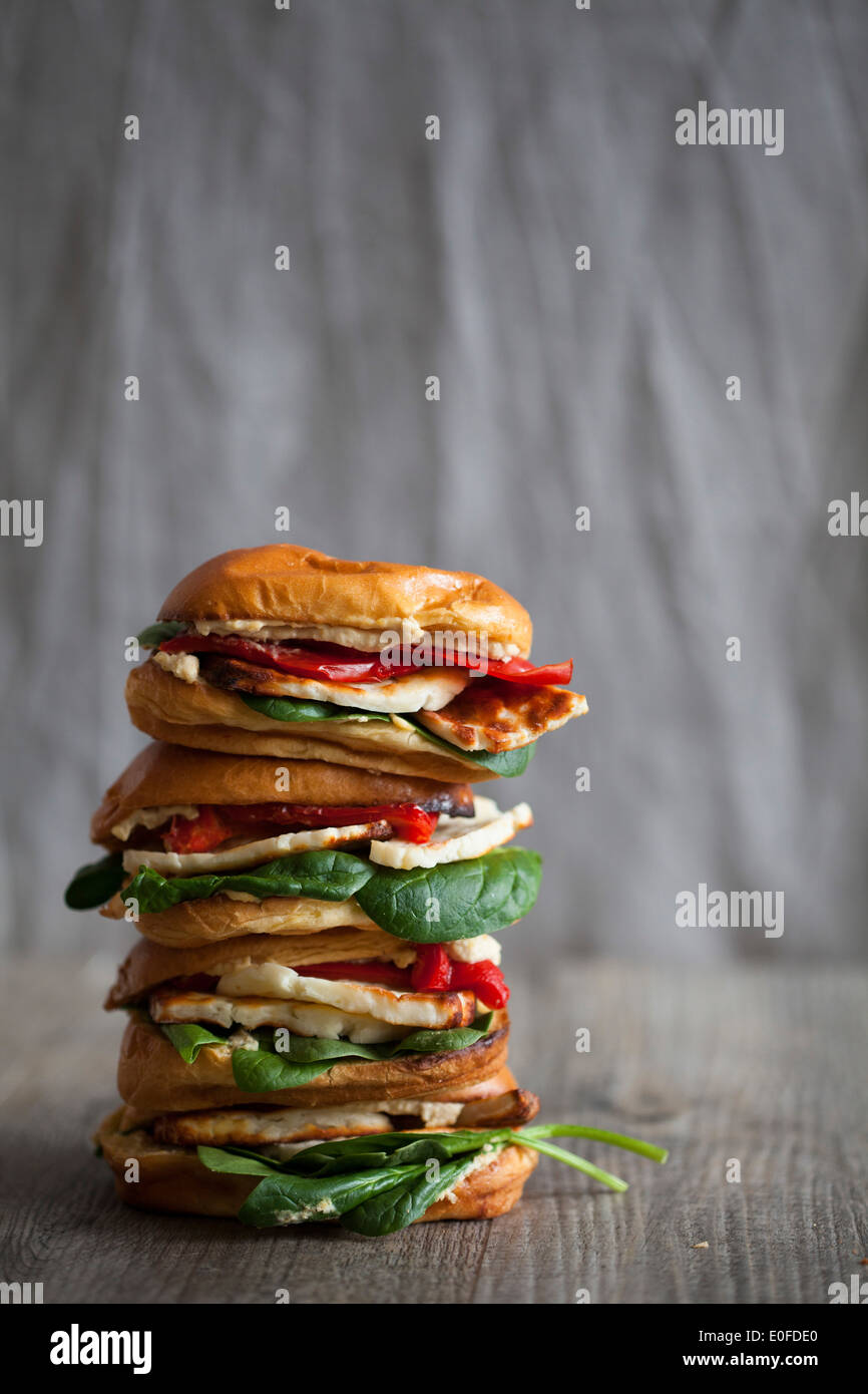 Una pila di halloumi, houmous e pepe rosso brioche burger Foto Stock