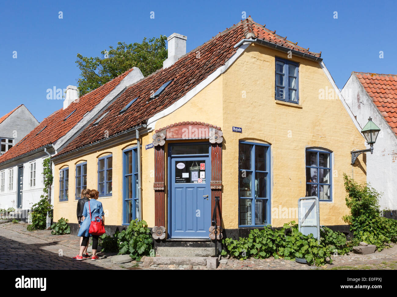 Due donne guardando un angolo shop in tipico vecchio edificio dipinto su Norrebakke, Ebeltoft, nello Jutland, Danimarca e Scandinavia Foto Stock