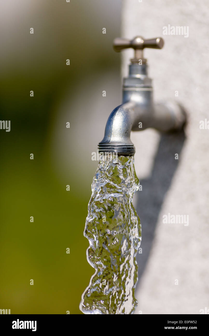 L'acqua che scorre dal all'aperto il rubinetto dell'acqua in una giornata di sole. Foto Stock