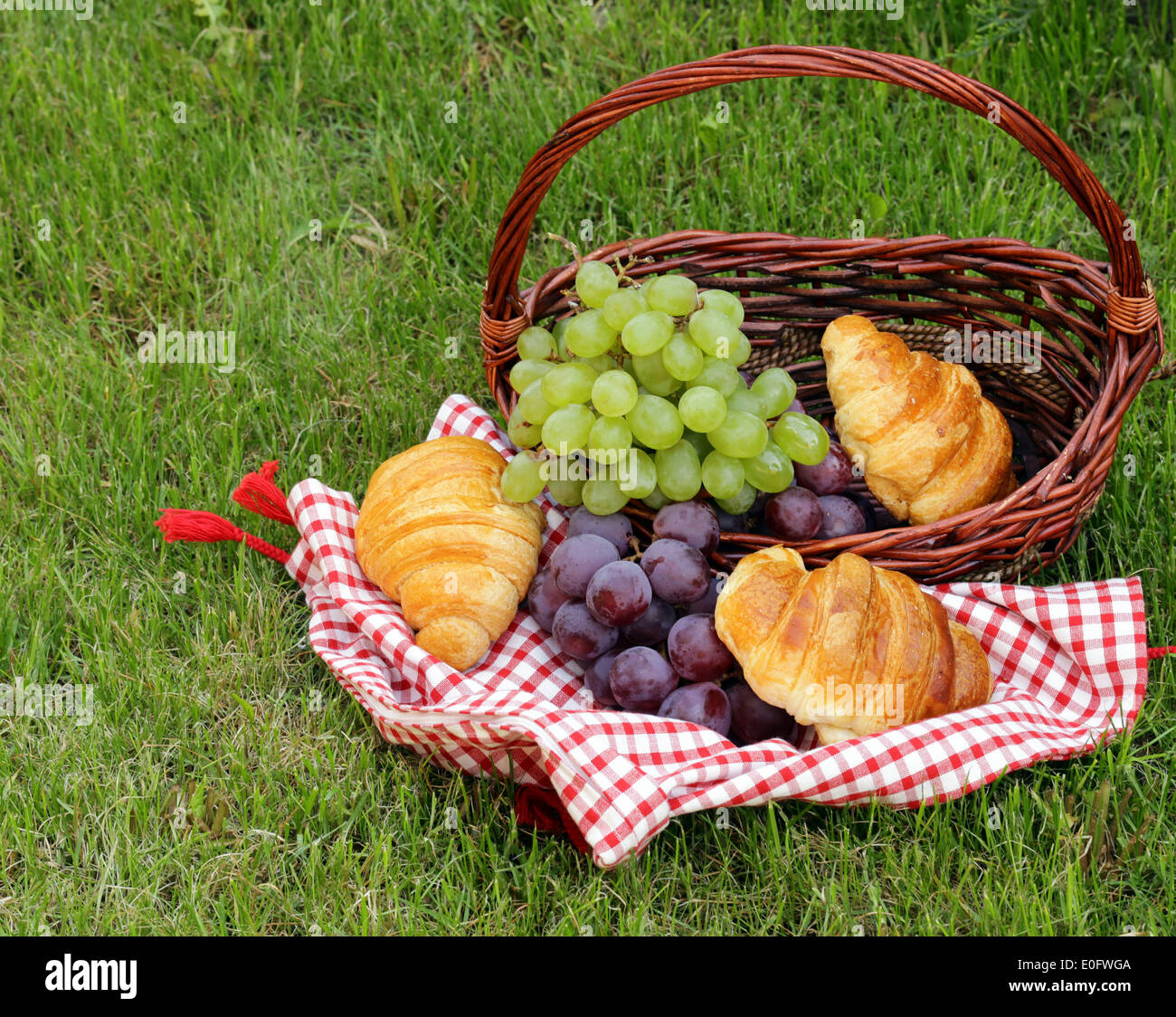 Pic nic sul prato verde con uve e croissant Foto Stock