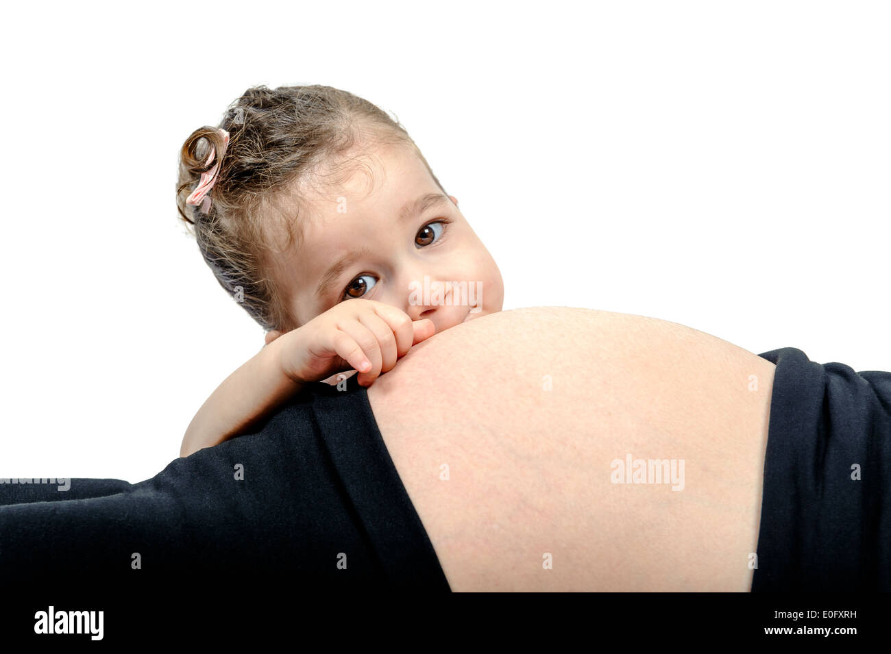 Primo bambino guardando oltre il suo madri incinte addome isolato su bianco Foto Stock