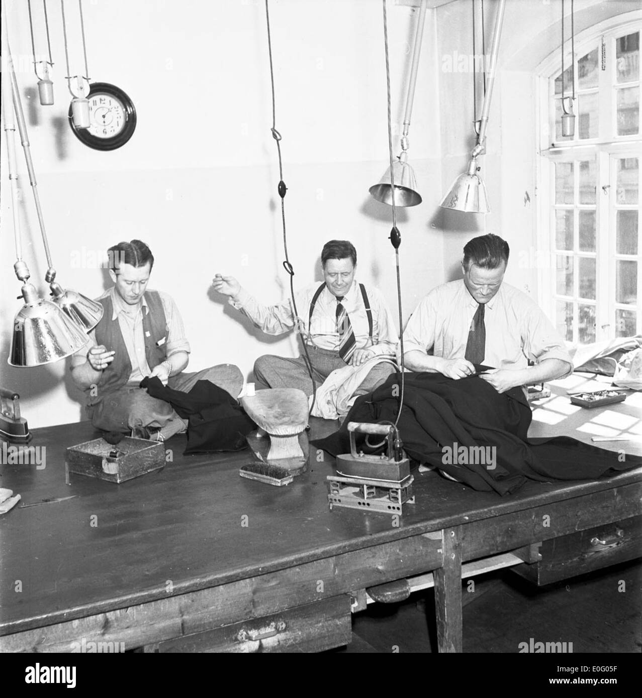 Una fotografia del 1948 che mostra un laboratorio di sartoria in un deposito di tram a Stoccolma. L'immagine cattura i lavoratori e gli strumenti utilizzati per la manutenzione e la riparazione delle uniformi dei tram, riflettendo l'era post-bellica del sistema di trasporto svedese. Foto Stock