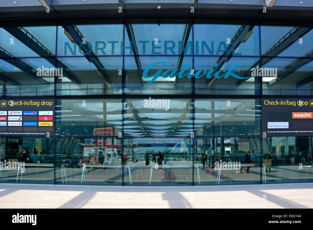 Entrata del Terminal Nord dell'Aeroporto di Gatwick Londra e cartello passeggeri all'interno visti attraverso i riflessi parete di vetro traslucido Crawley West Sussex Inghilterra Regno Unito Foto Stock