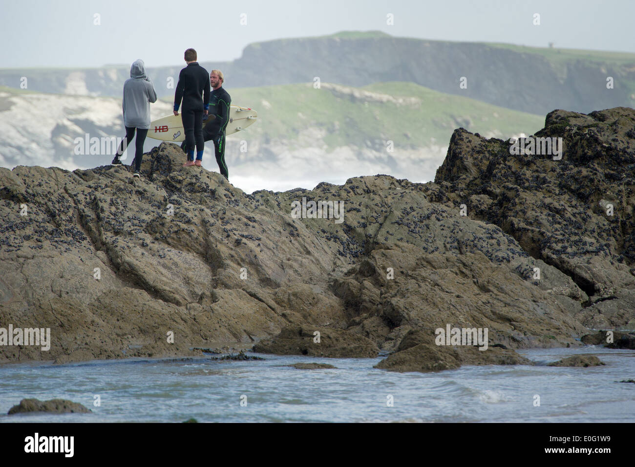 Tre adolescenti stare su una roccia a Newquay, Cornwall, Inghilterra. Foto Stock