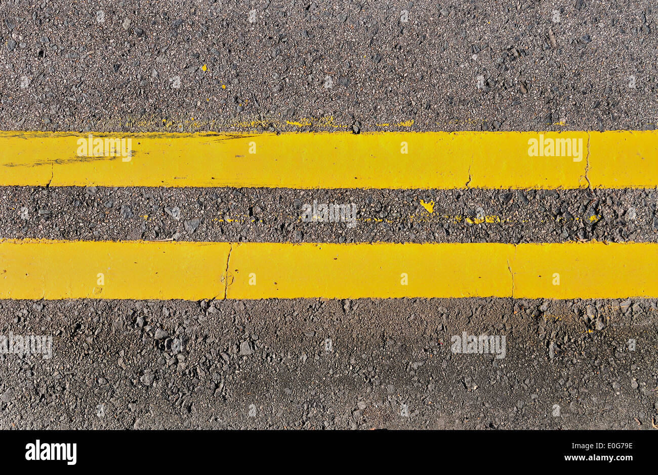 Doppio giallo linee che corrono orizzontalmente su una strada asfaltata. Foto Stock