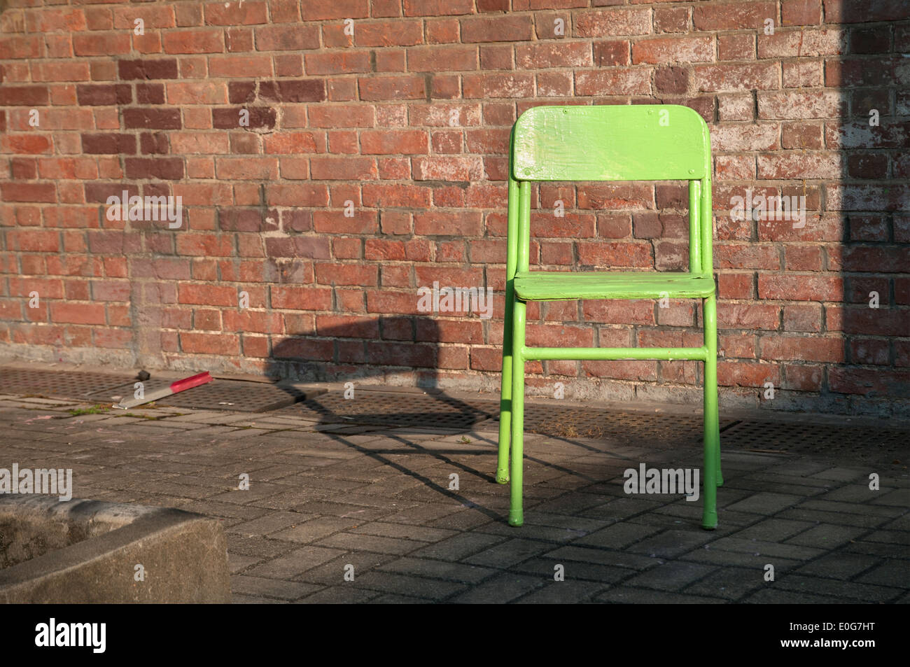 Vecchia sedia verde accanto a un esterno di un muro di mattoni Foto Stock