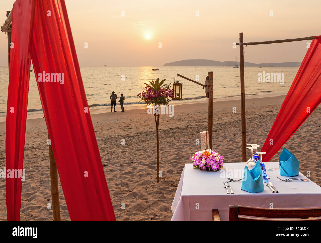 Serata romantica tavolo per due persone sulla spiaggia al tramonto. Foto Stock