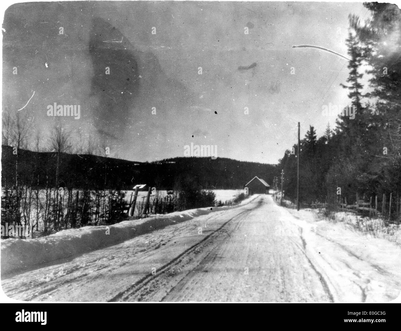 Questa immagine raffigura una strada innevata dell'inverno 1924-1925, che mostra la manutenzione della strada da parte di Brødrene Øveraasen. Mette in evidenza il paesaggio innevato, con le nevi che sgommano le strade durante i duri mesi invernali, sottolineando l'uso di macchinari nella manutenzione stradale durante i primi anni del XX secolo. Foto Stock
