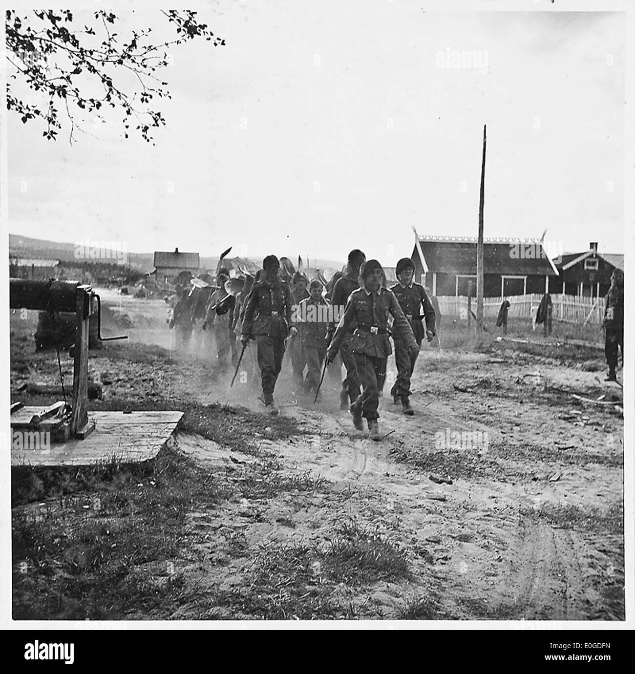 Questa immagine mostra un'impresa di costruzioni che sta marciando in un quartiere durante la seconda guerra mondiale, probabilmente in Norvegia. La scena cattura l'attività militare e il ruolo delle imprese di costruzione durante il periodo della guerra, contribuendo agli sforzi militari e allo sviluppo delle infrastrutture. Foto Stock