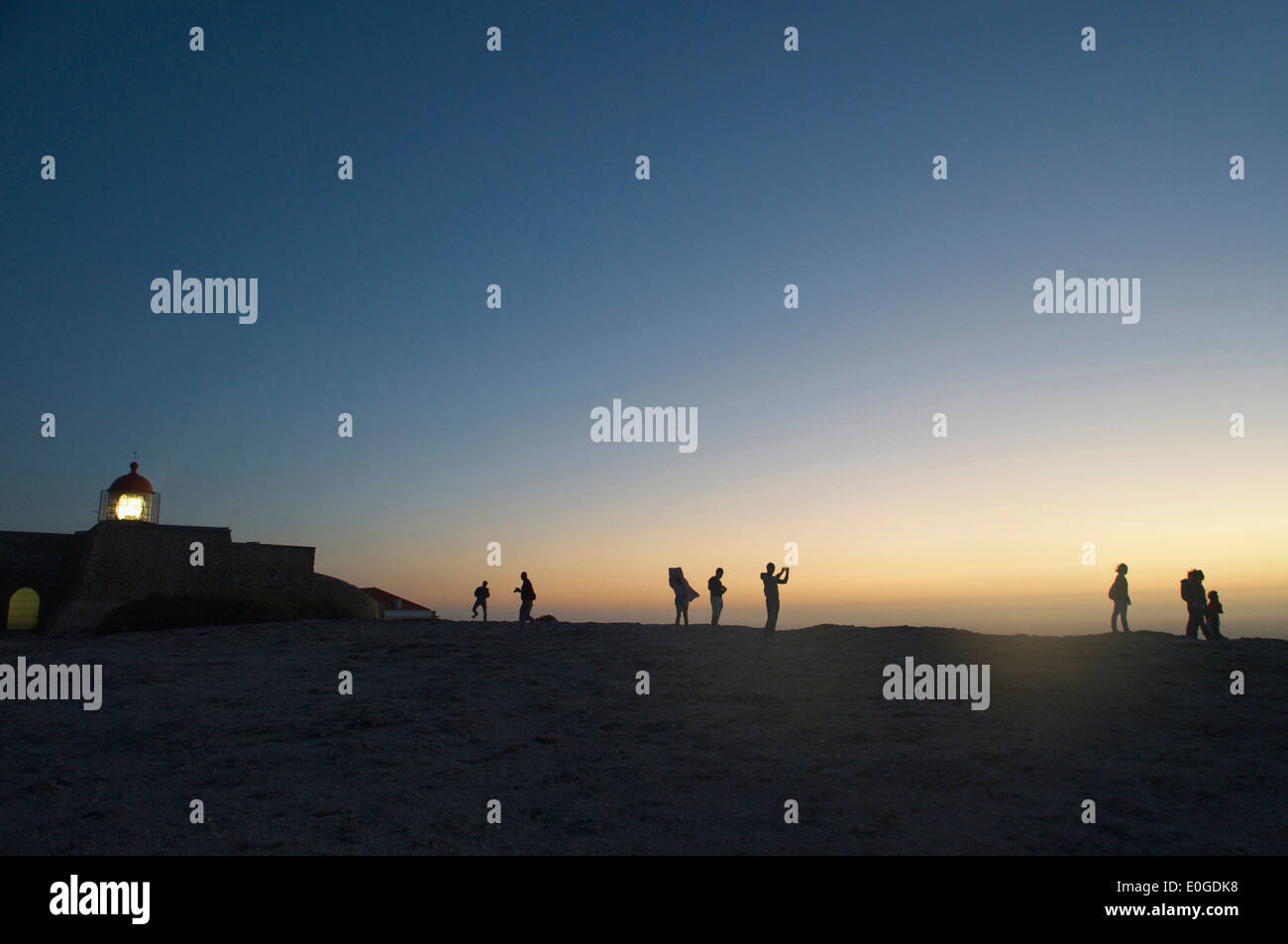 Casa di luce e persone come sagome su alta rupe, Cabo de Sao Vicente, atmosfera serale, Algarve, Portogallo, Europa Foto Stock