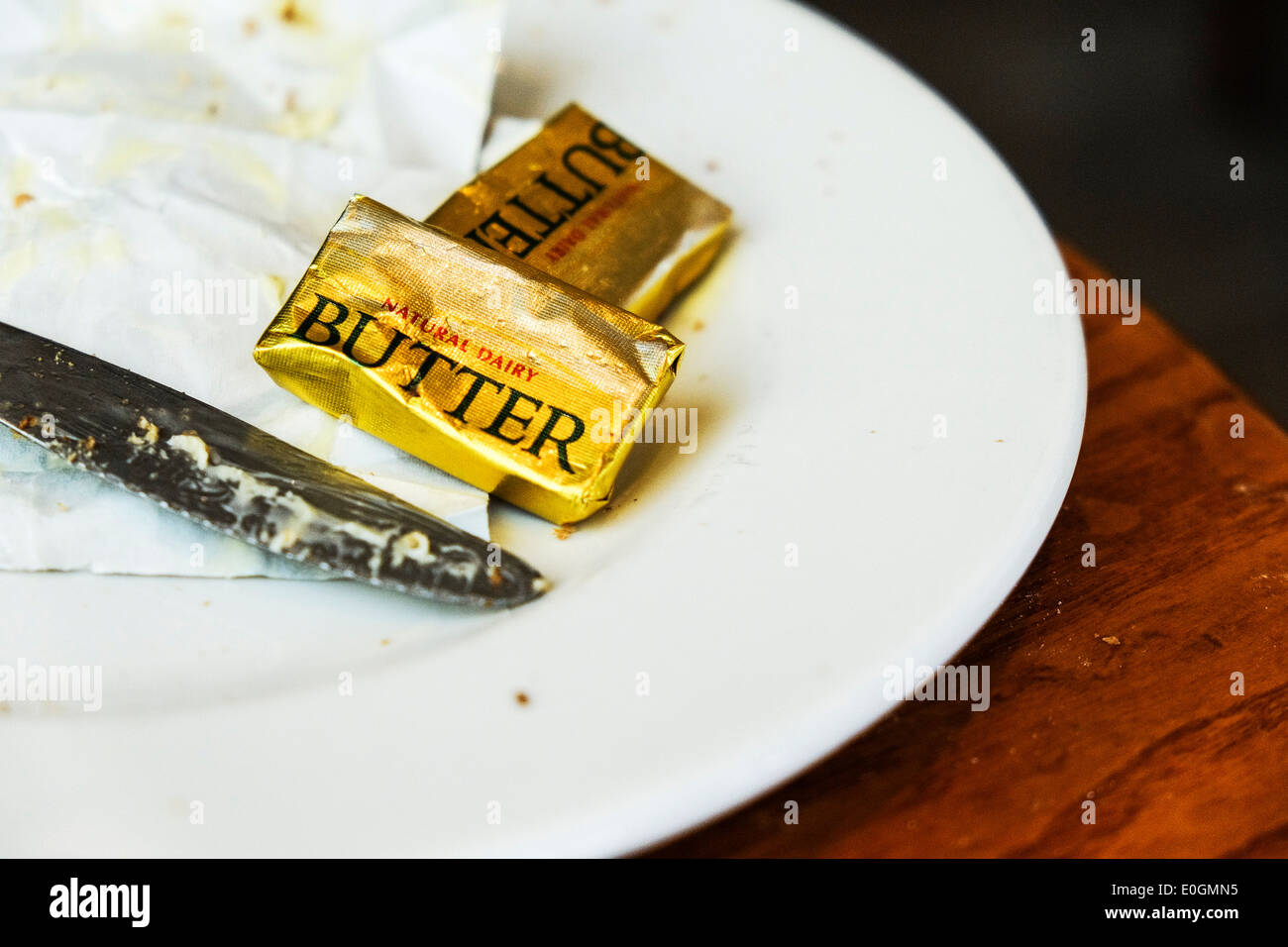 Piccoli pacchetti di burro su una piastra. Foto Stock