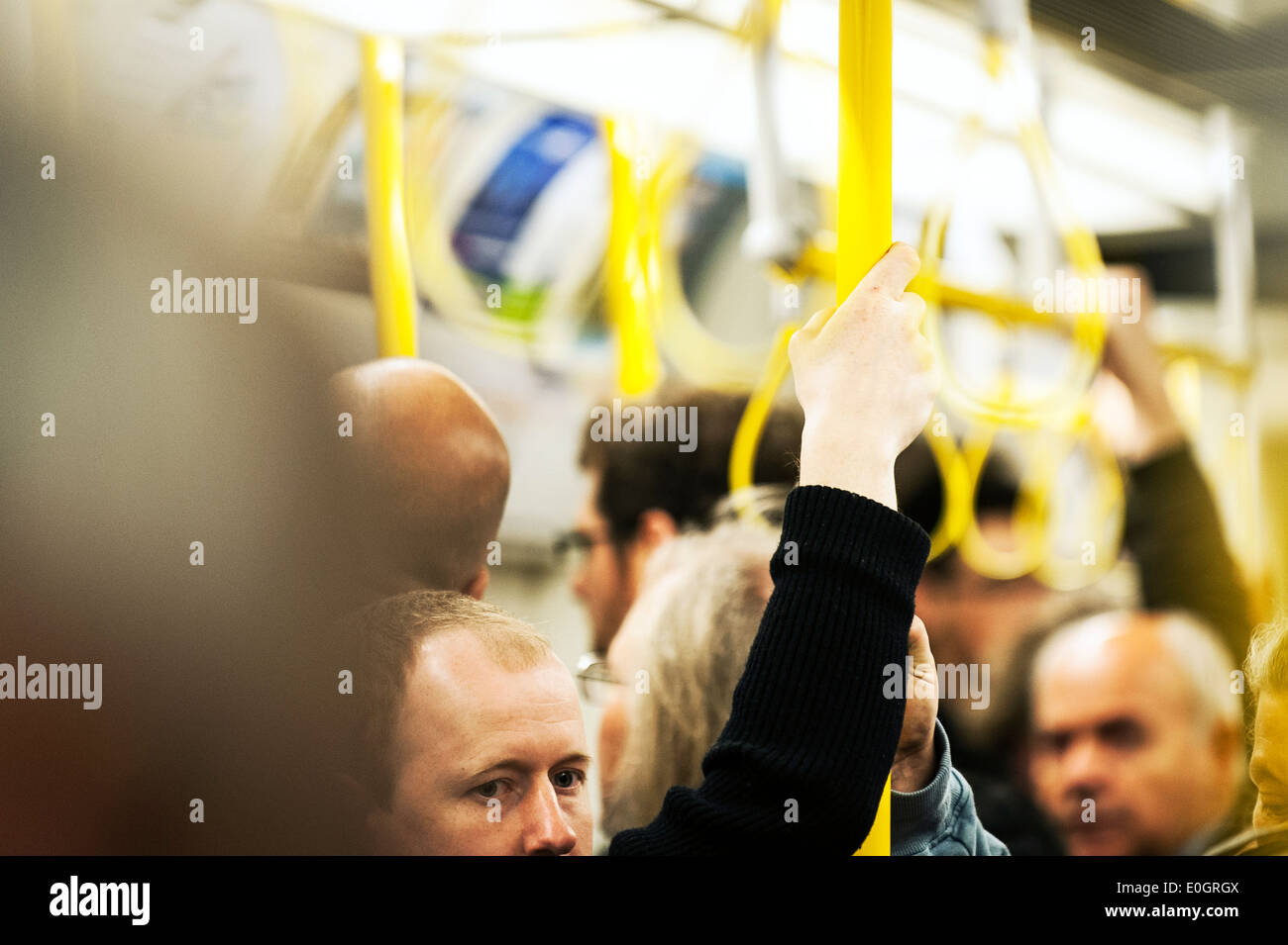 Un " commuter " tenuta su di un post su un affollato Londra della metropolitana treno. Foto Stock