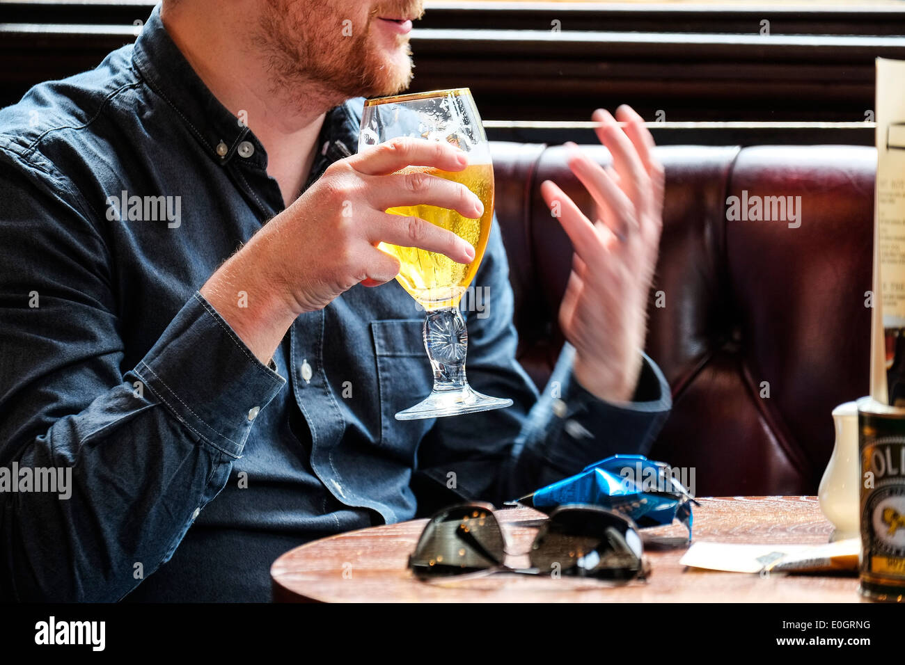 Un uomo in un pub bevendo birra lager. Foto Stock