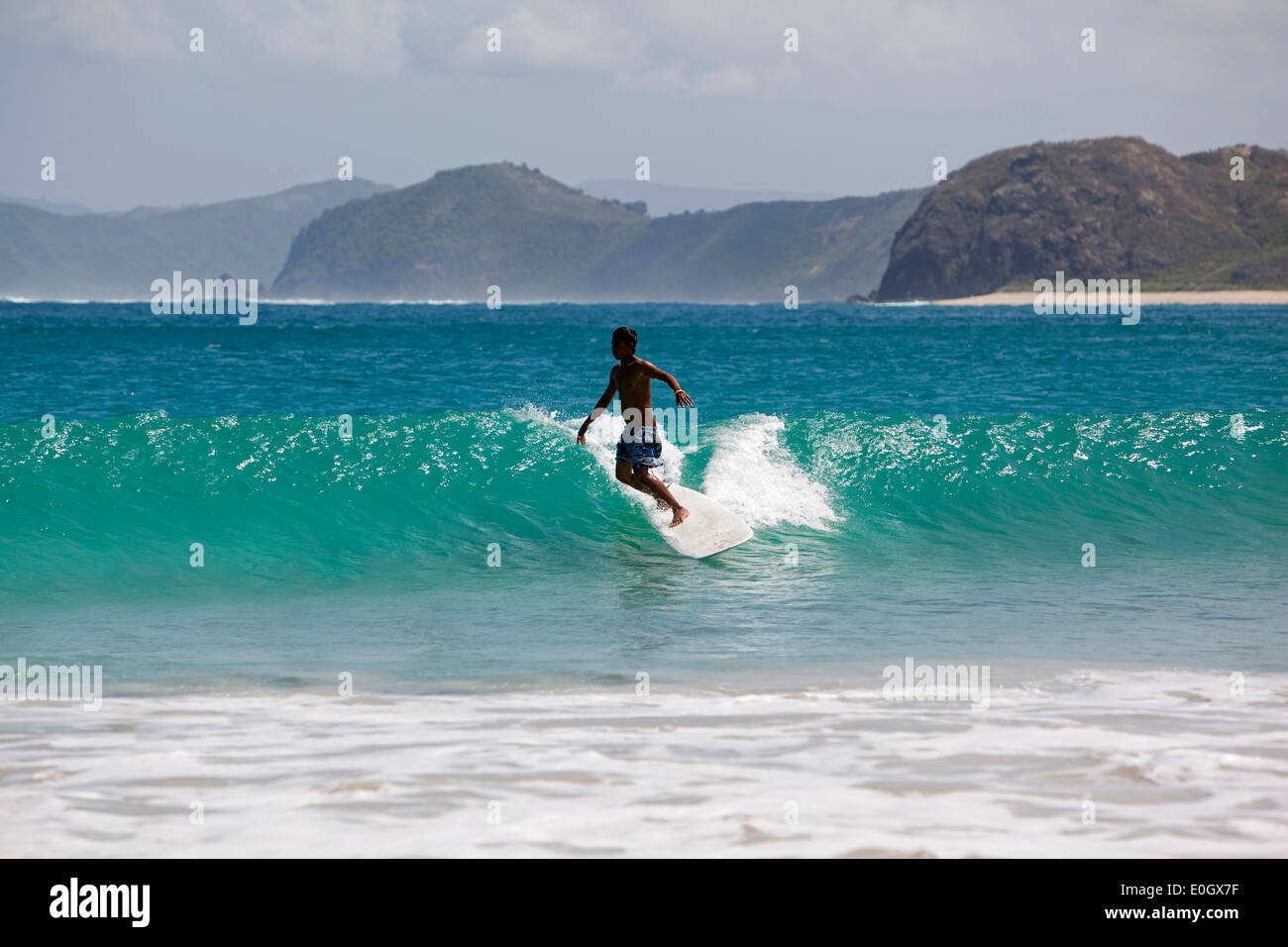 Indonesia, Lombok, South Coast, Seong Blanak, spiaggia, giovane surfista locale surf Foto Stock