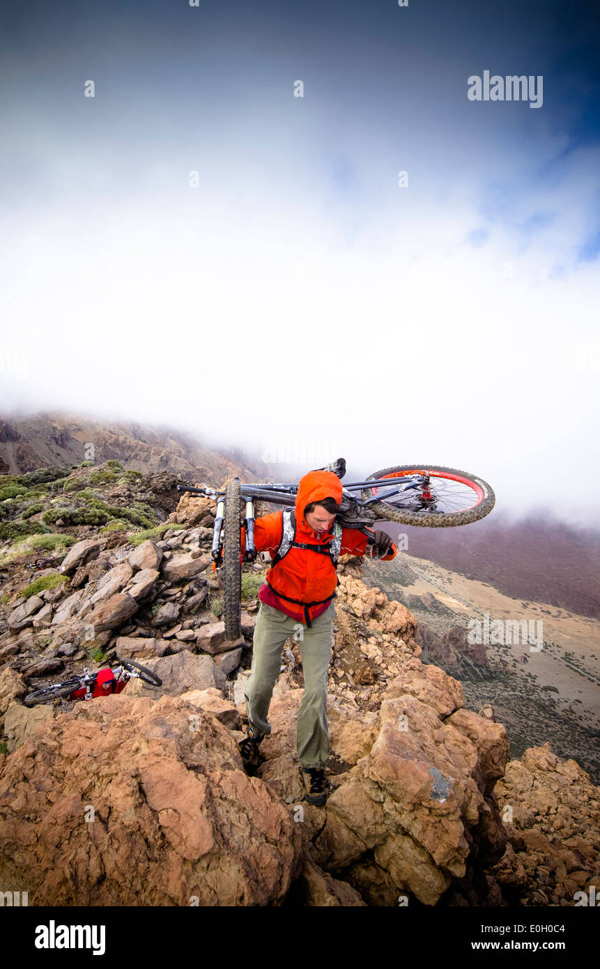 Gli uomini che trasportano mountain bike su una cresta, Tenerife Foto Stock