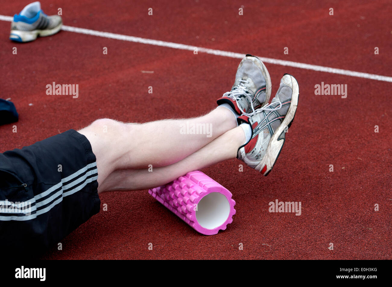 Atleta usando il rullo di schiuma per i muscoli del polpaccio Foto Stock
