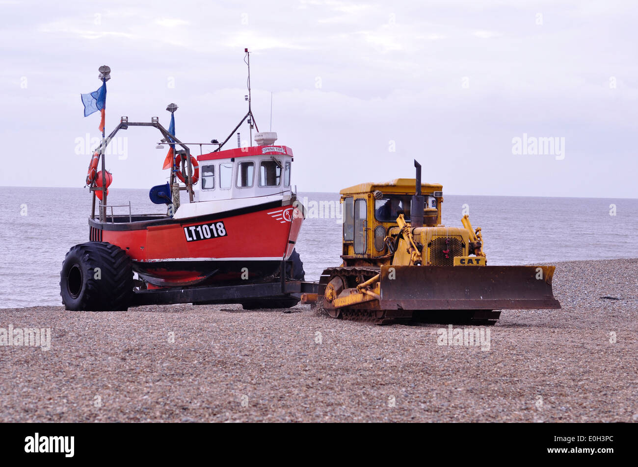 Barca da pesca di essere portato fino alla spiaggia di bulldozer e rimorchio a Aldeburgh, Suffolk Foto Stock