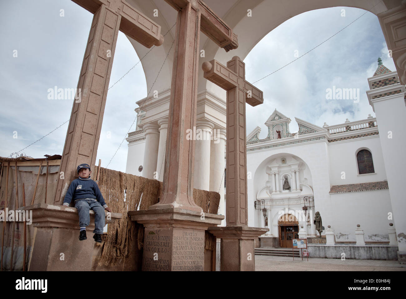 Ragazzo seduto a una croce davanti alla Basilica della Vergine nera, Virgen Morena, Copacabana, lago Titicaca, Bolivia, Ande, Sout Foto Stock